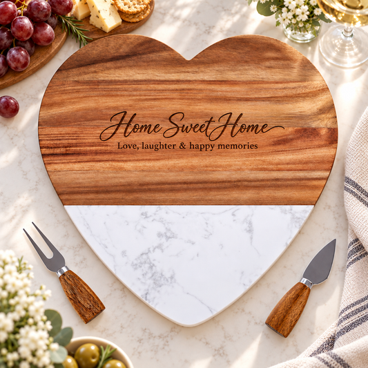 Heart-shaped serving board with natural wood upper section, white marble base, and matching cheese knife and fork on a white background\.