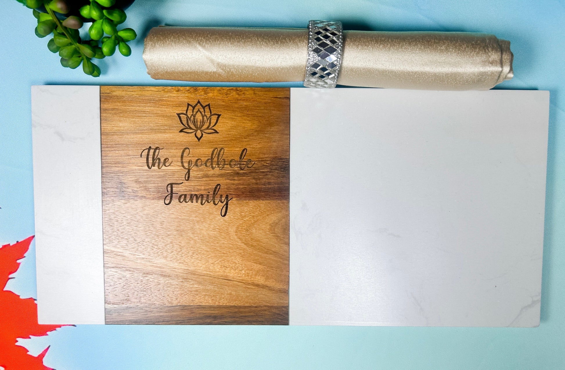 Wooden cutting board with engraved text, white paper, and silver roll of paper on a blue background