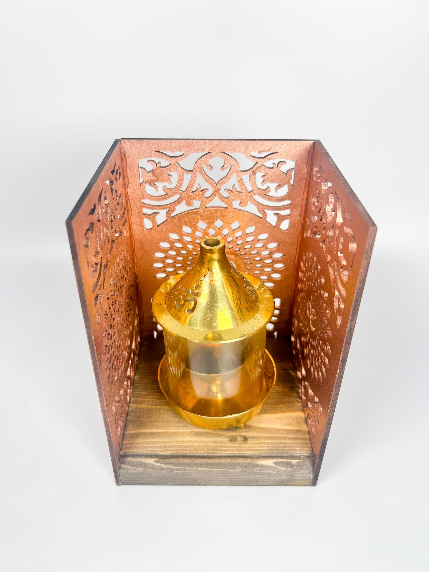Decorative lantern with intricate cut-out design and a gold candle holder on a white background