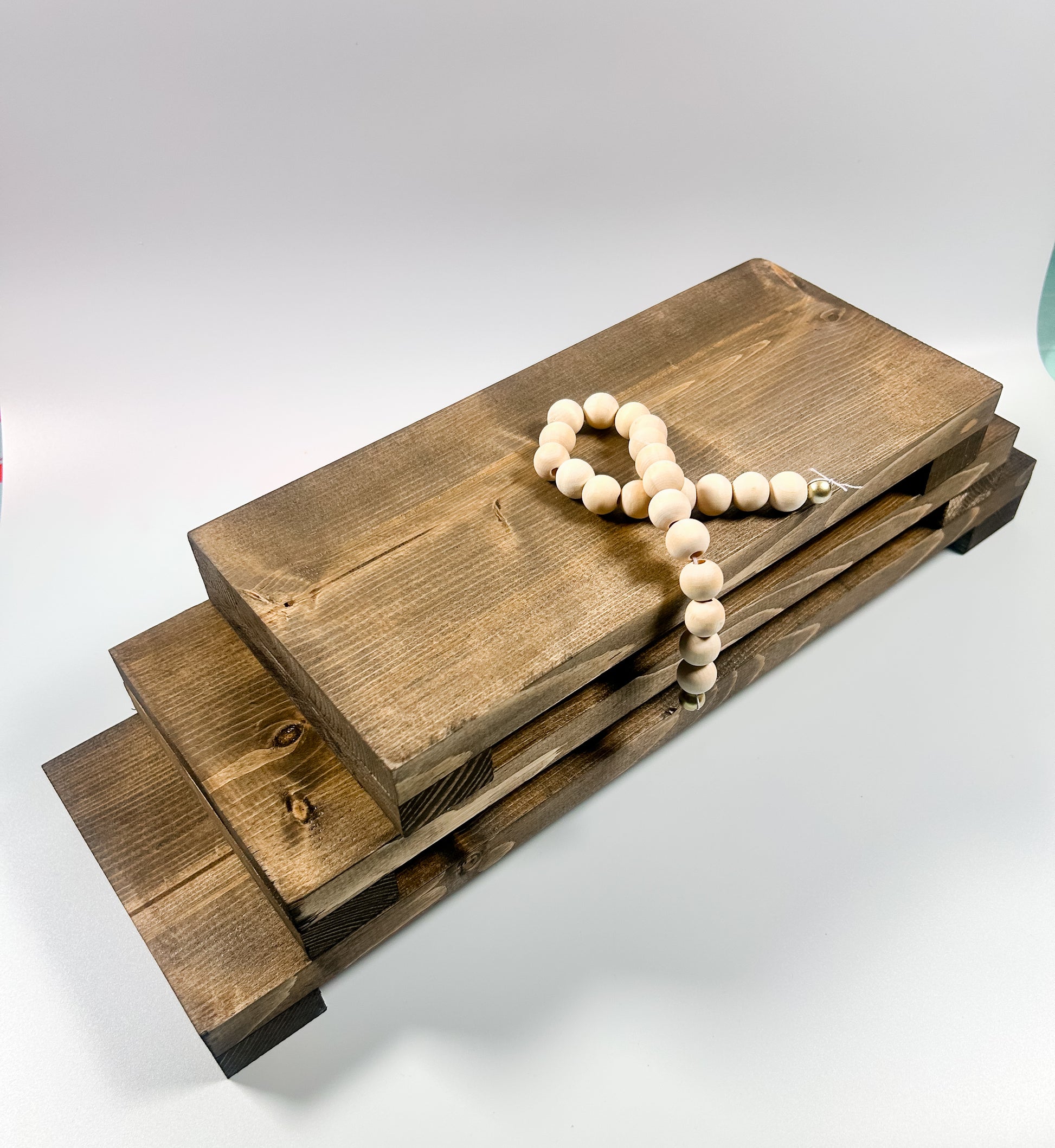 Handcrafted long wooden pedestal riser displaying candles and greenery on a farmhouse kitchen countertop.